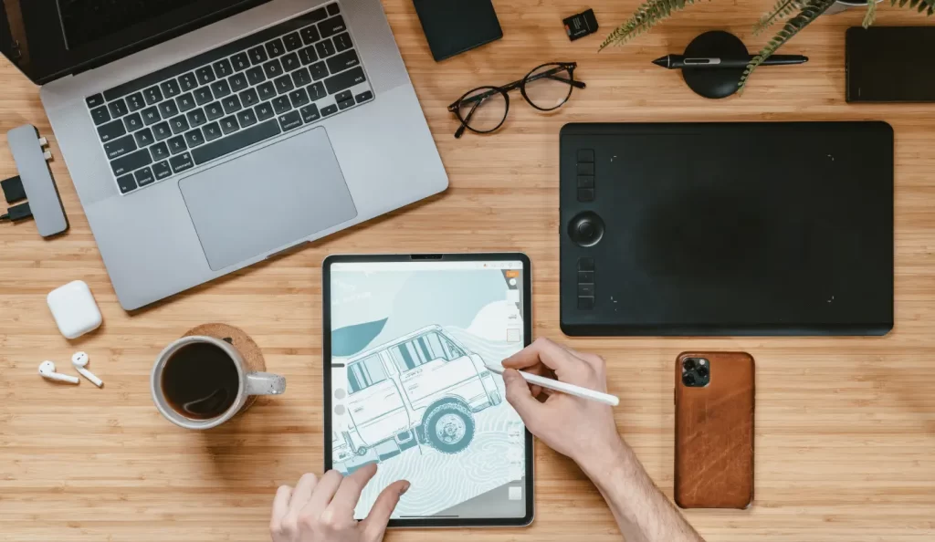 artist-drawing-car-tablet-surrounded-by-gadgets