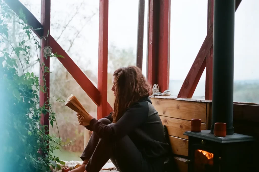 girl-reading-book-beside-fireplace