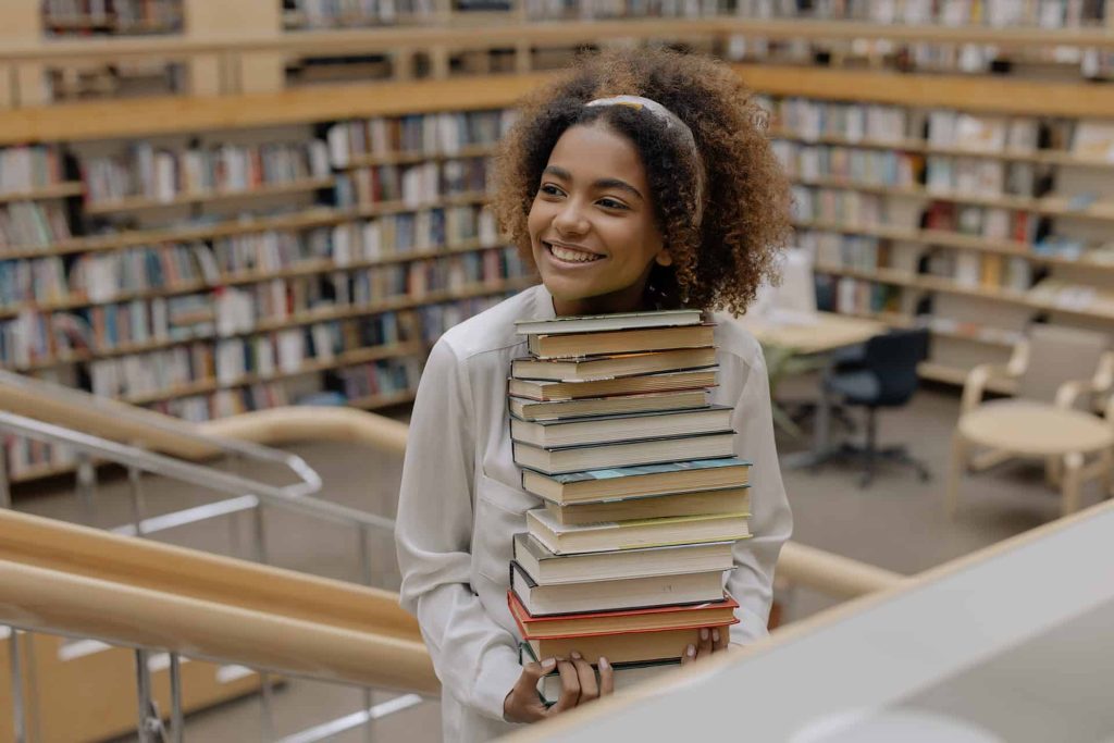 happy-girl-carrying-stacks-of-books