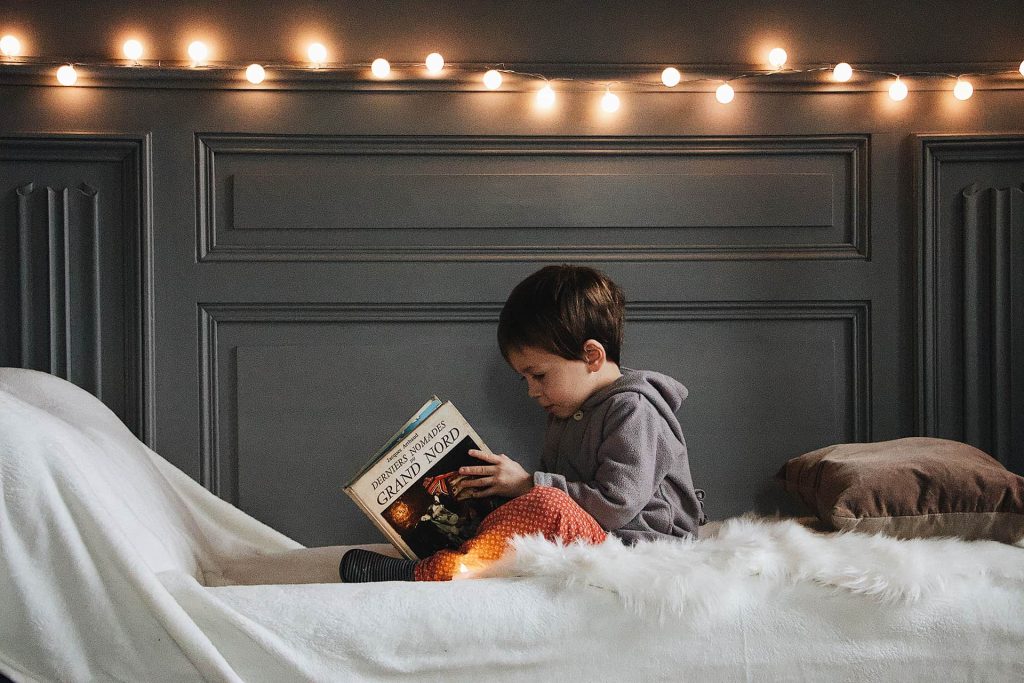 kid-reading-book-on-bed-with-lights