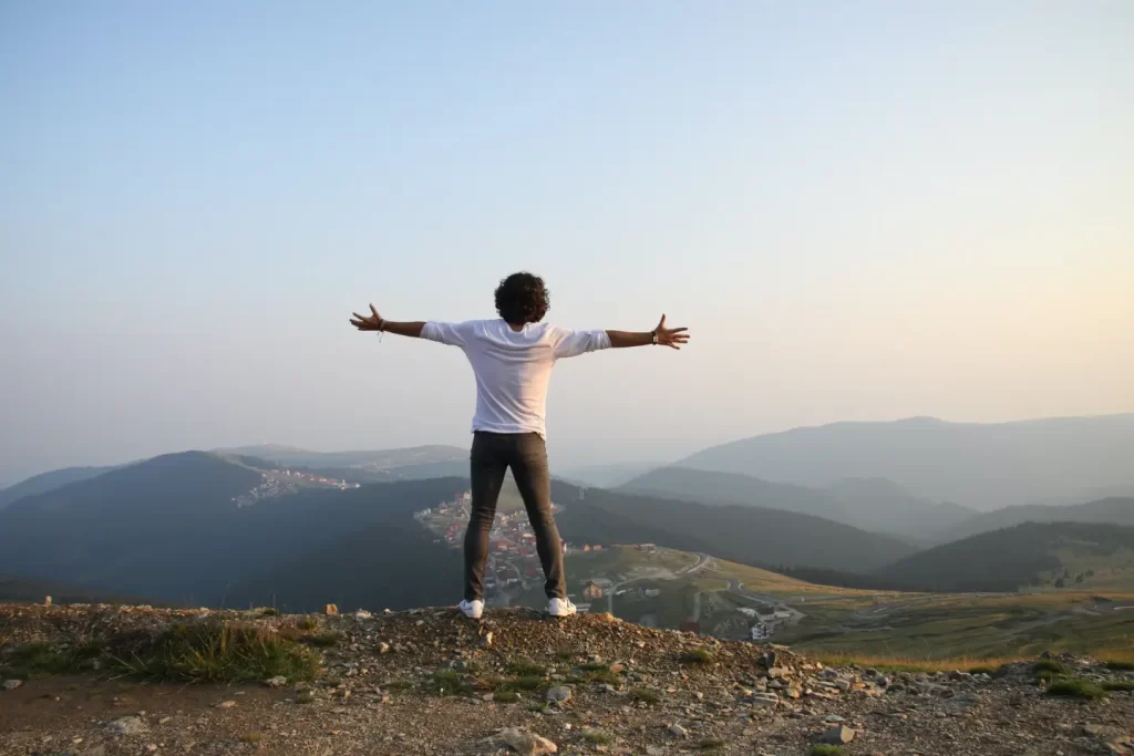 man-open-wide-arms-mountain-view