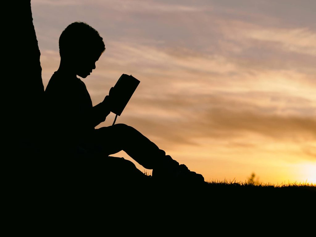 silhouette-kid-reading-under-tree-sunset