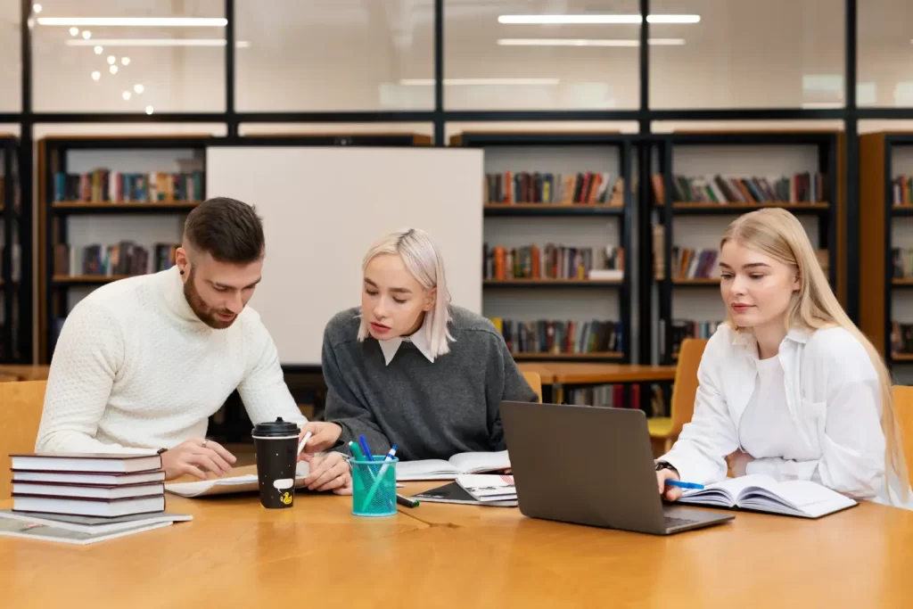 three-friends-studying-from-documents-laptop-library