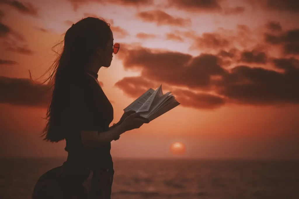 woman-standing-holding-open-book-looking-sea