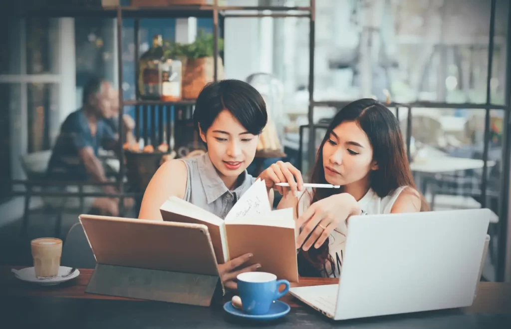 women-checking-notebook-coffee-shop