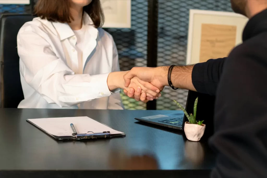 a-man-and-a-woman-shaking-hands-in-front-of-a-laptop