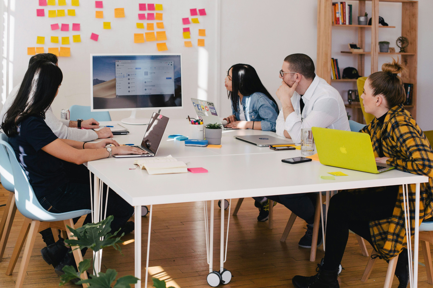 five-person-by-table-watching-turned-on-white-imac