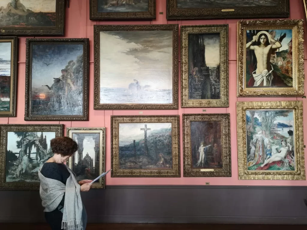 woman-in-white-long-sleeve-shirt-standing-in-front-of-paintings